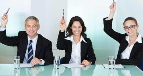 business people at table with hands raised