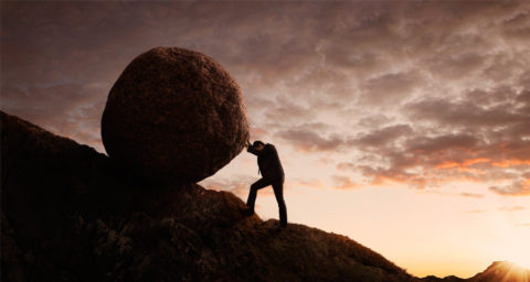 business man pushing a rock up a hill